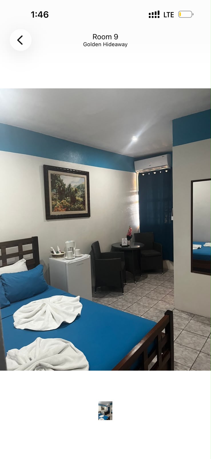 Teal-accented guest room with a double bed, mini-fridge and seating nook