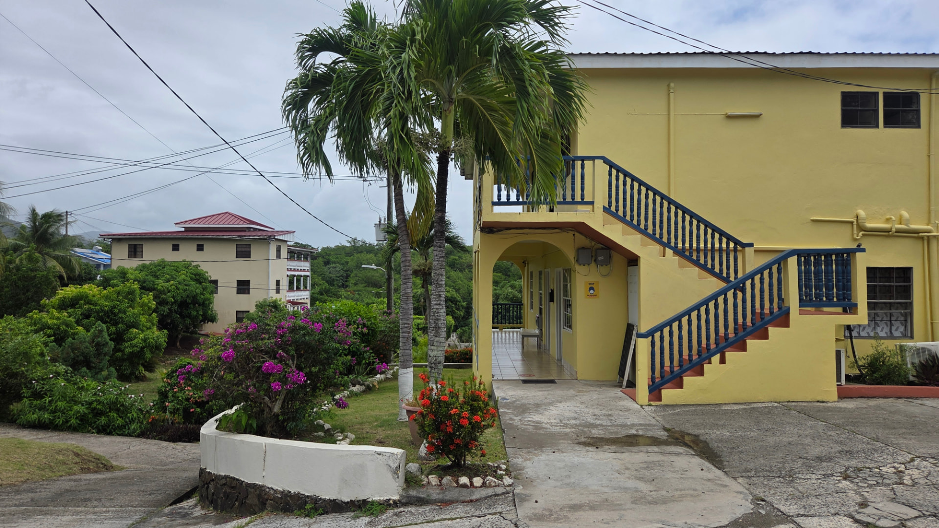The inn's arched entrance with blue stairway railings and palm trees